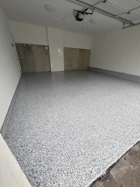 Comet flake epoxy floor in a two-car garage with wood storage doors in Burnaby, BC