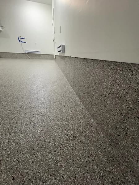 Close-up of a Creek Bed flake epoxy cove base in a Vancouver garage