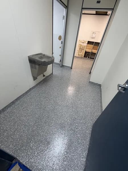 Grey flake epoxy floor in a commercial hallway with a wall-mounted water fountain