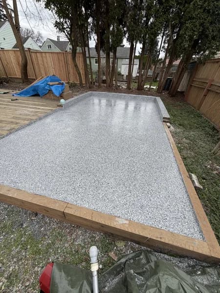 Freshly coated grey and white flake epoxy patio in a fenced backyard