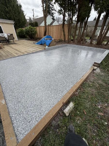 Outdoor grey flake epoxy patio installed beside a backyard wood deck