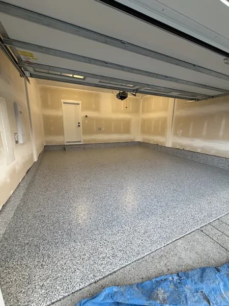 Newly coated grey and white flake epoxy floor in an unfinished two-car garage