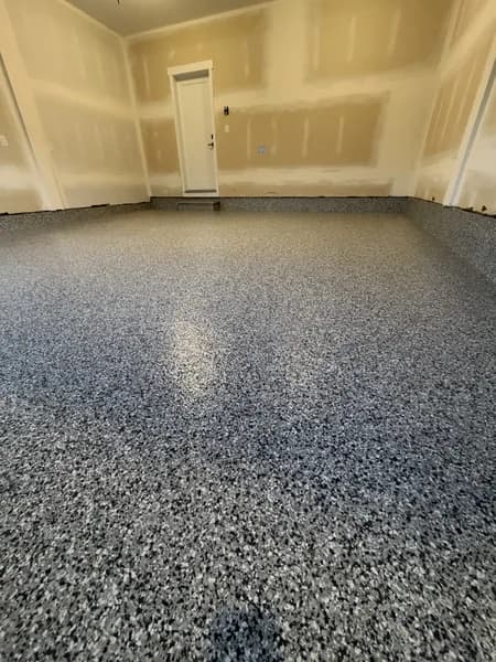 Blue-grey flake epoxy floor in a garage with taped drywall walls