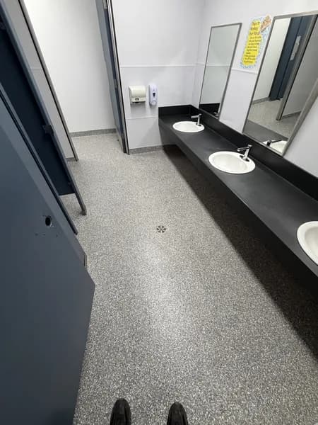 Grey flake epoxy floor in a commercial restroom with a double vanity
