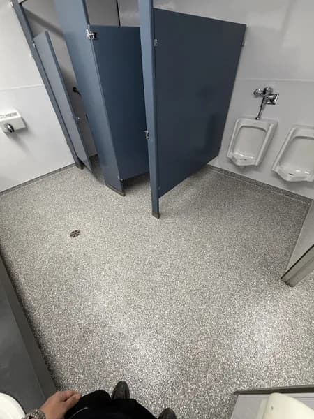 Grey flake epoxy floor in a commercial restroom with stalls and urinals