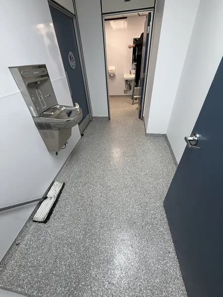 Grey flake epoxy floor in a commercial corridor leading to a restroom
