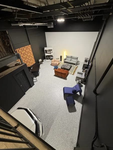 Light grey flake epoxy floor in a modern studio lounge with black walls