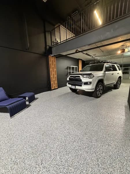 Grey flake epoxy showroom floor with a white SUV and lounge seating