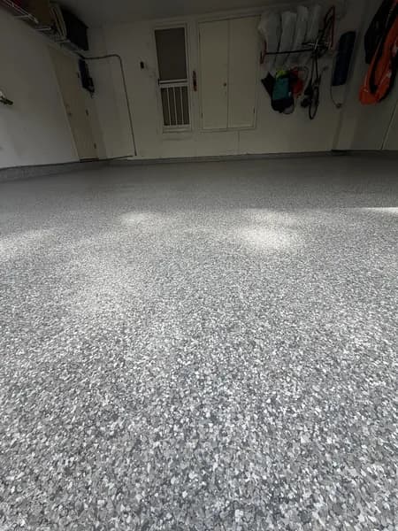 Silver-grey flake epoxy garage floor with gear hung by the entry door