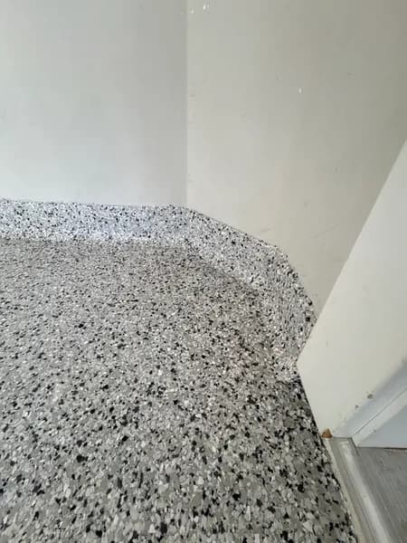 Gracious flake epoxy floor curving up into a cove base in Langley, BC
