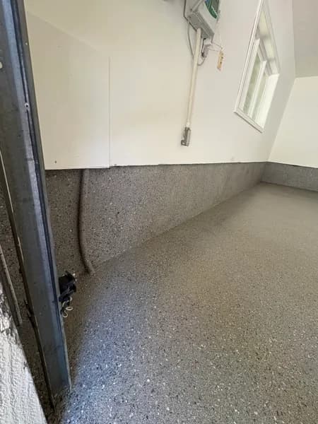 Hybrid flake epoxy garage floor and cove base in a West Vancouver garage corner