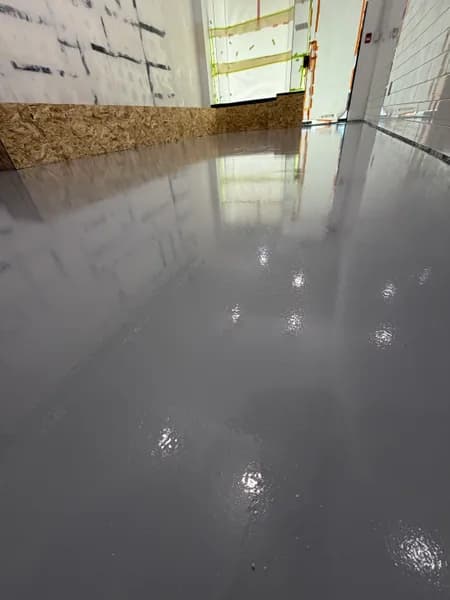Close-up of a glossy grey solid epoxy commercial floor reflecting the storefront windows in Vancouver, BC