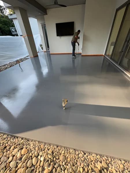 Grey solid epoxy covered patio beside river rock landscaping in Maple Ridge, BC