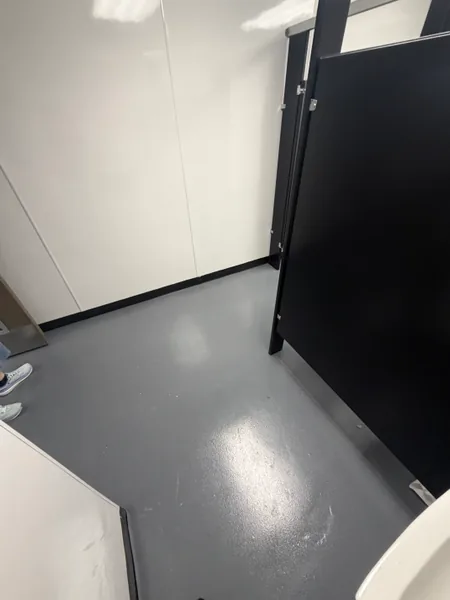 Grey solid epoxy washroom floor beside a stall partition in Coquitlam, BC